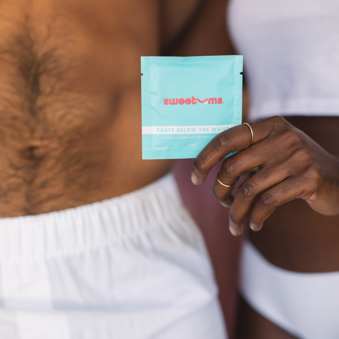 woman holding a cinnamon bun flavored intimate wipe while standing next to a man