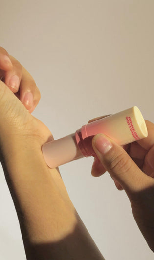 a hand applying stick based solid fragrance on their wrist