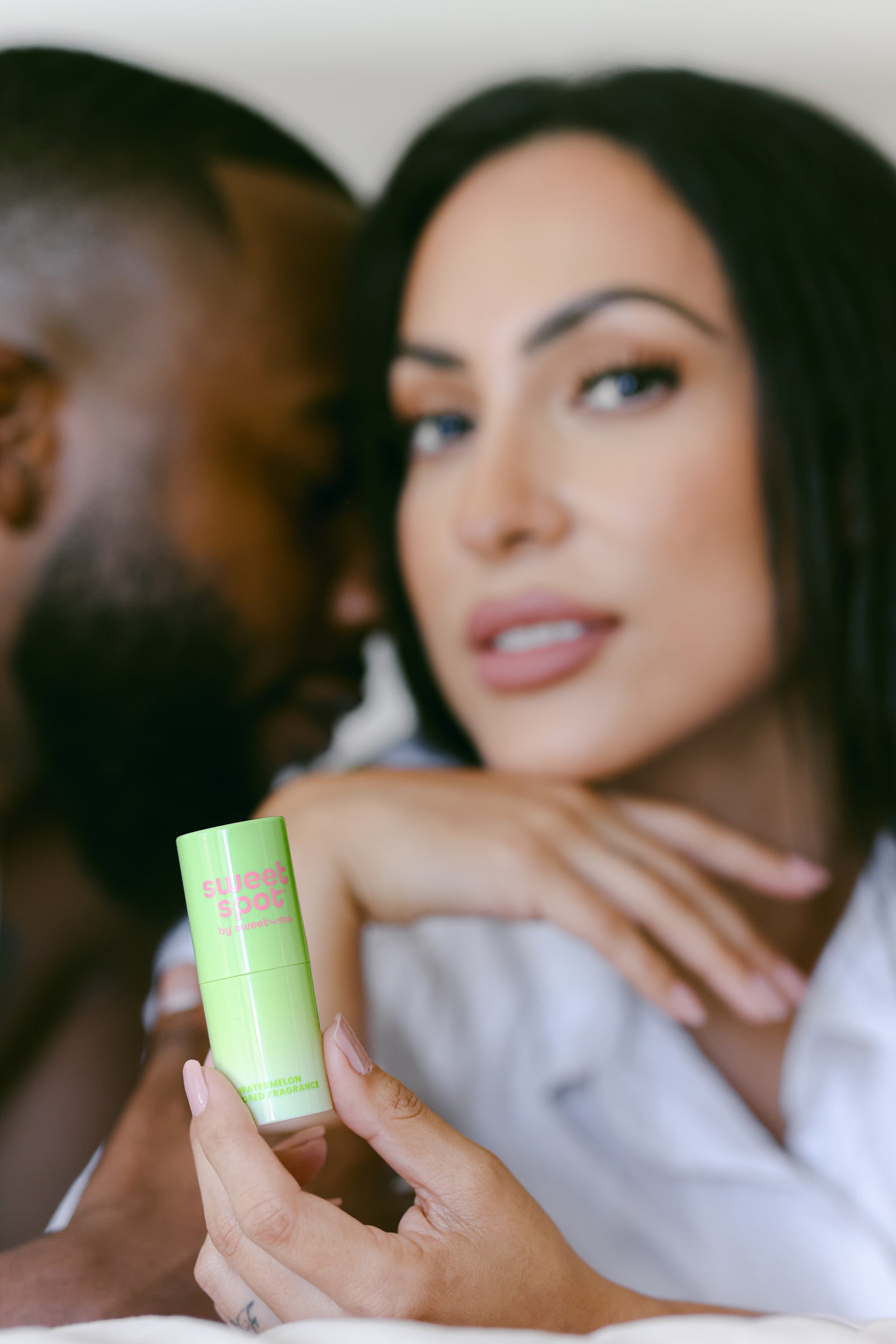 woman holding watermelon sweet spot fragrance while a man smells her neck