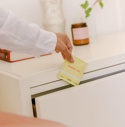 woman pulling a pina colada sweetums wipe out of a bedside table
