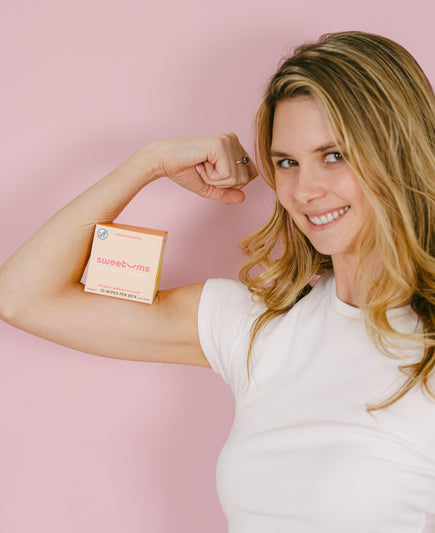 woman holding sweetums wipes on her arm and smiling