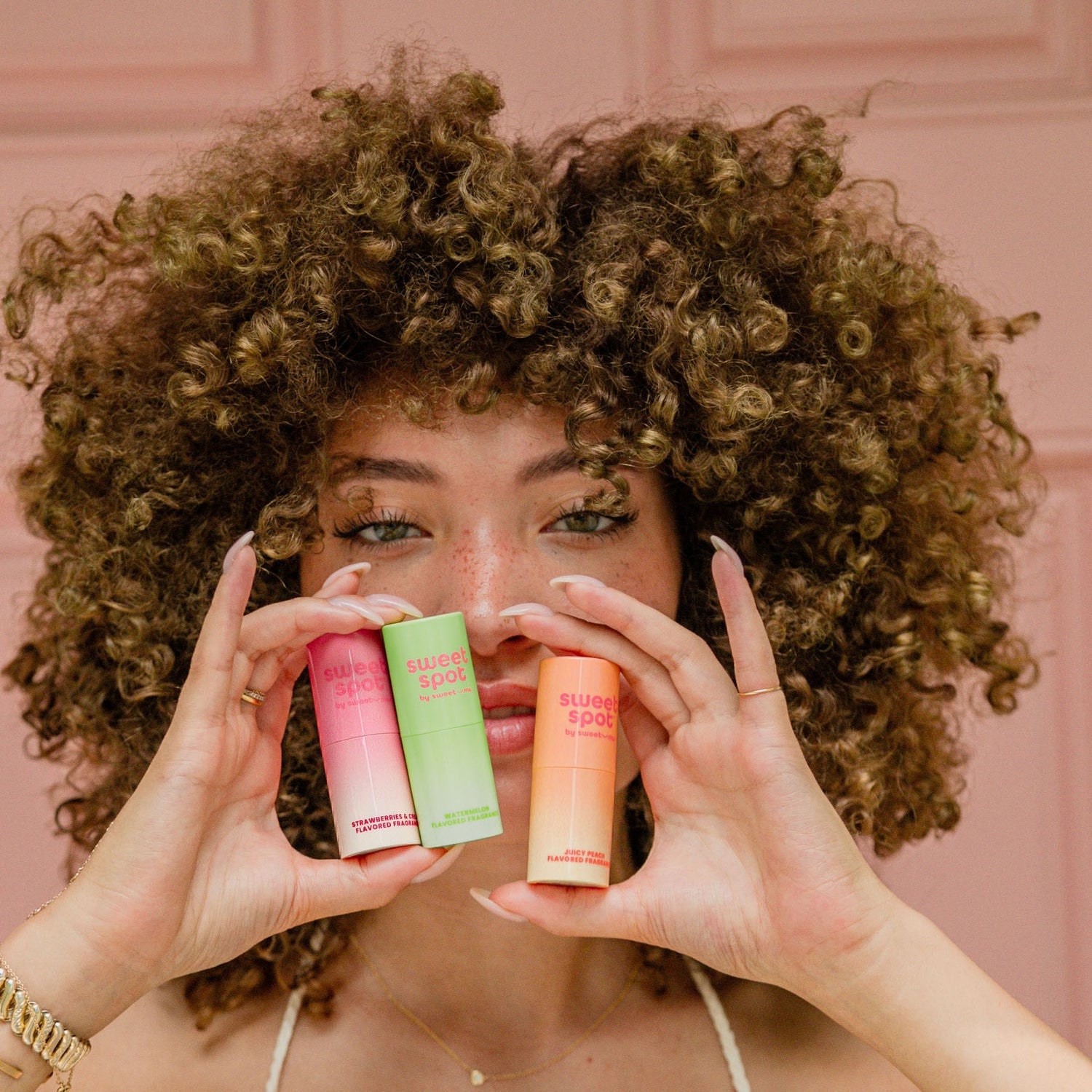 woman holding sweet spot flavored fragrances in front of her face