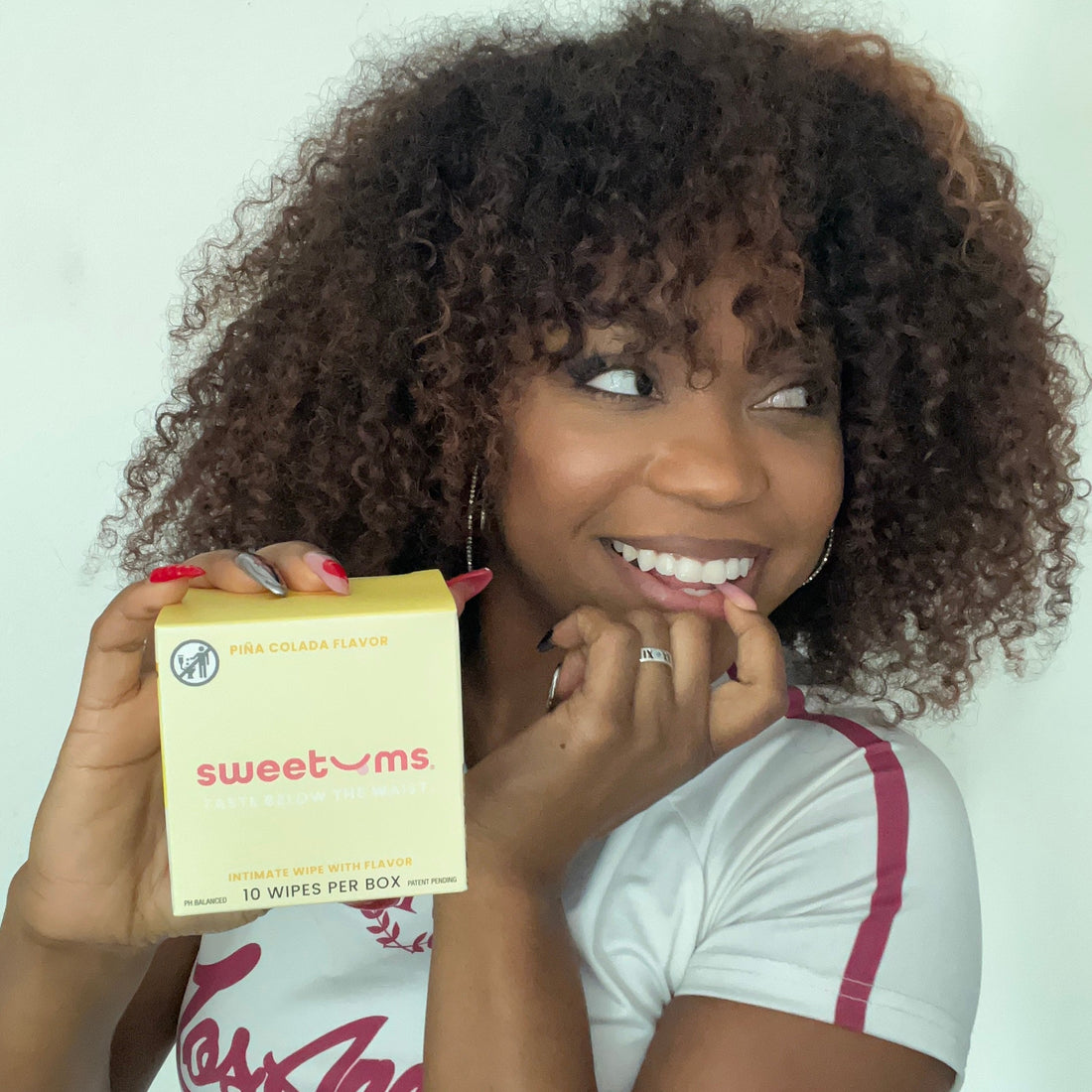 Woman holding a box of 'sweetums' products against a white background
