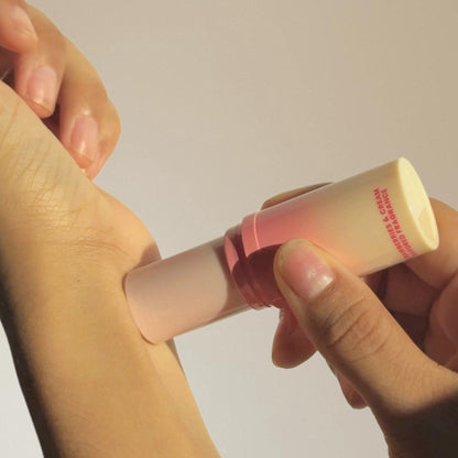 Hand applying sweet spot solid stick fragrance to another hand against a neutral background