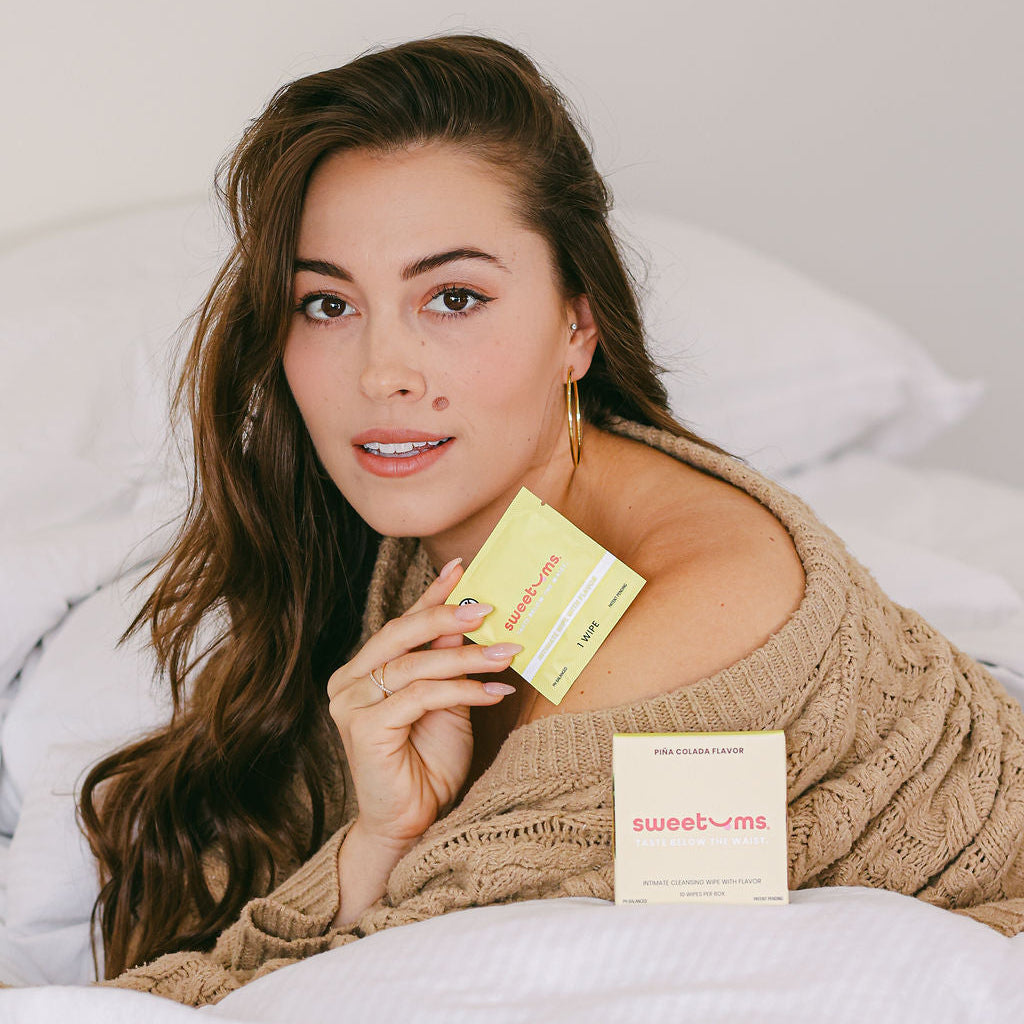 a woman holding a pineapple flavored intimate wipe