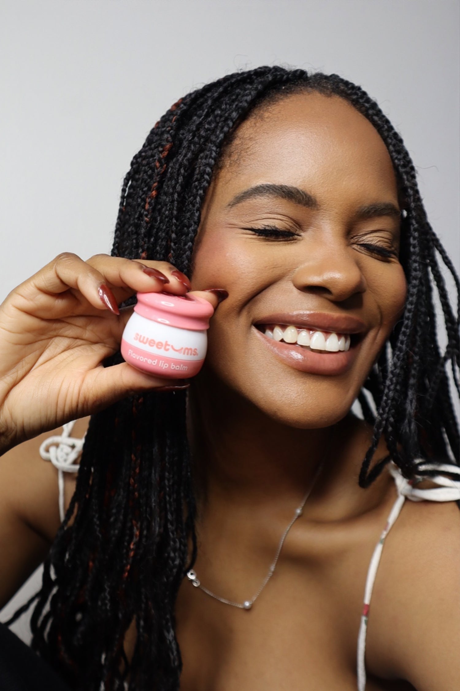 Woman holding cherry flavored lip balm and smiling