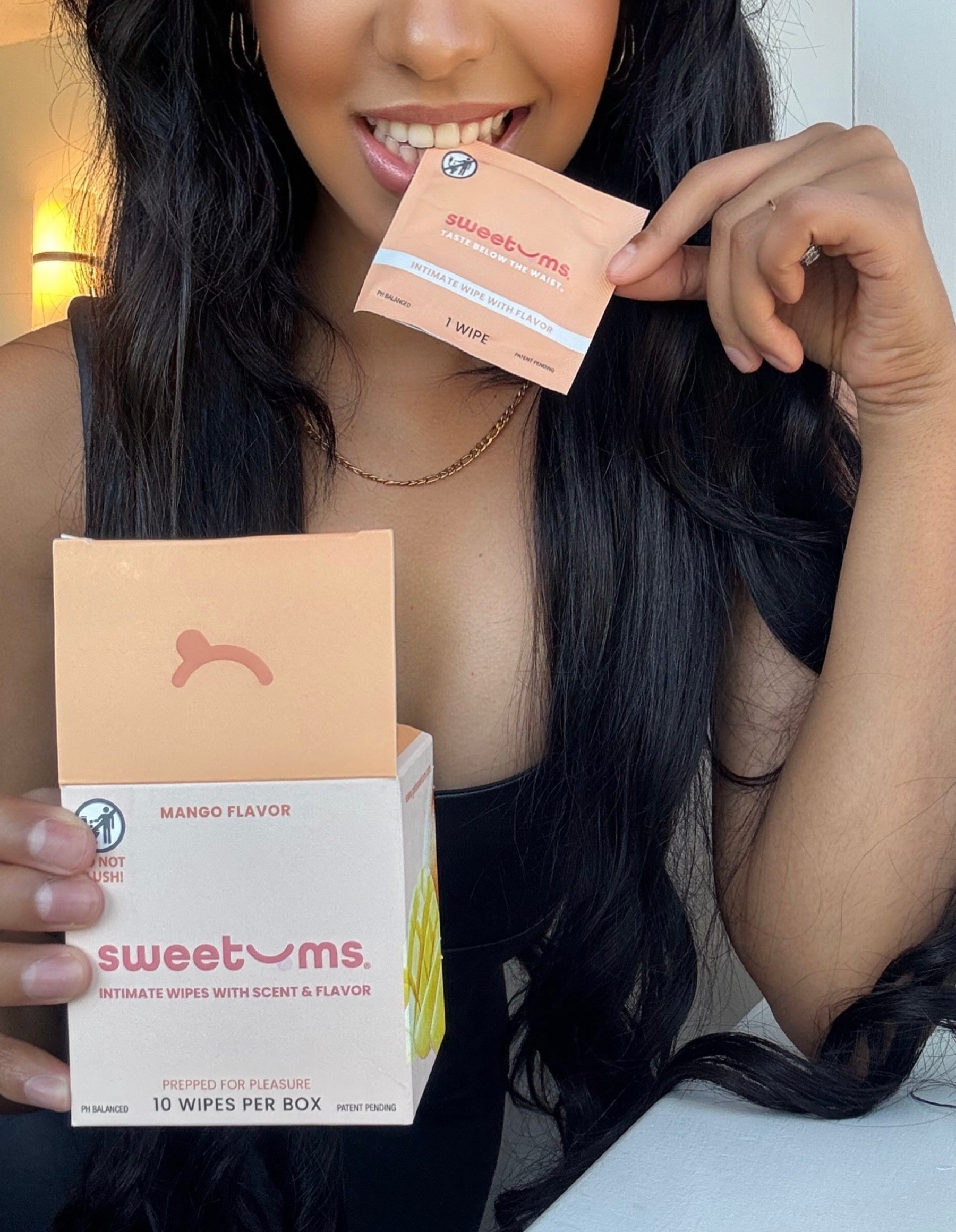 Person holding a box and a packet of sweetums intimate wipes.