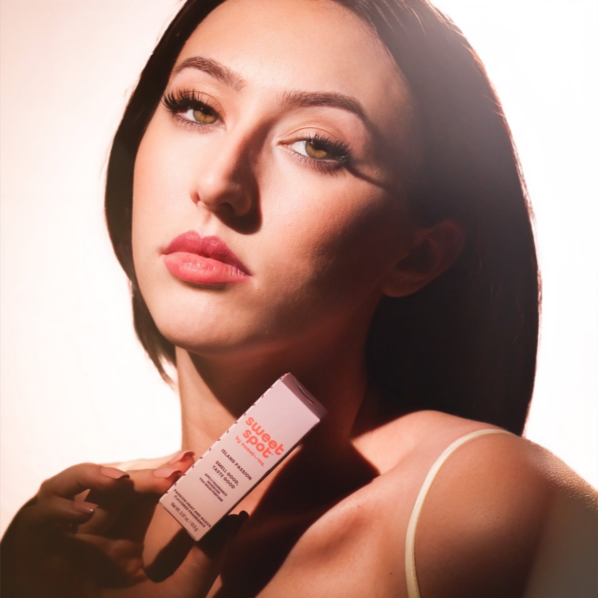 Woman holding a Island Passion Sweet Spot fragrance product with a neutral background