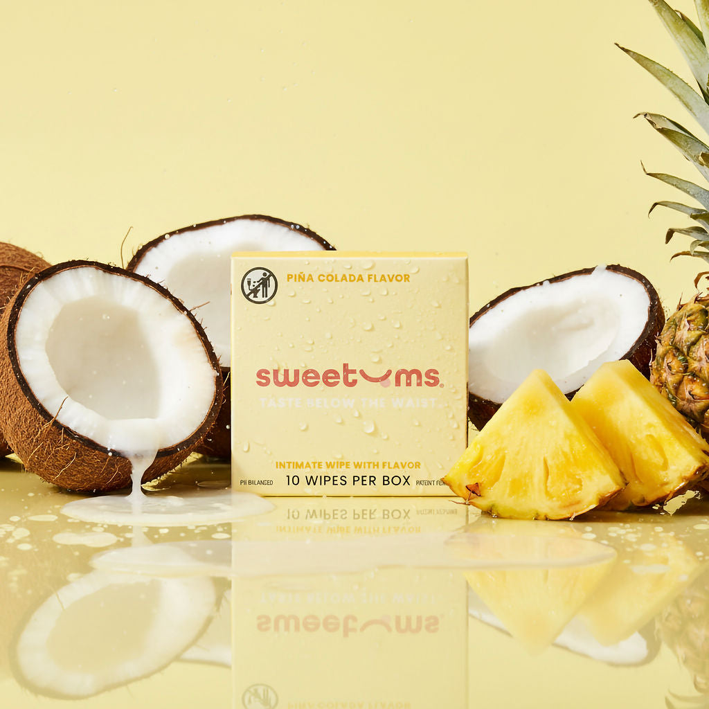Box of sweetums wipes with pina colada flavor surrounded by coconuts and pineapple on a yellow background