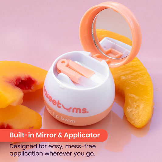 Sweetums peach flavored lip balm with built-in mirror and applicator on a pink background with peach slices.