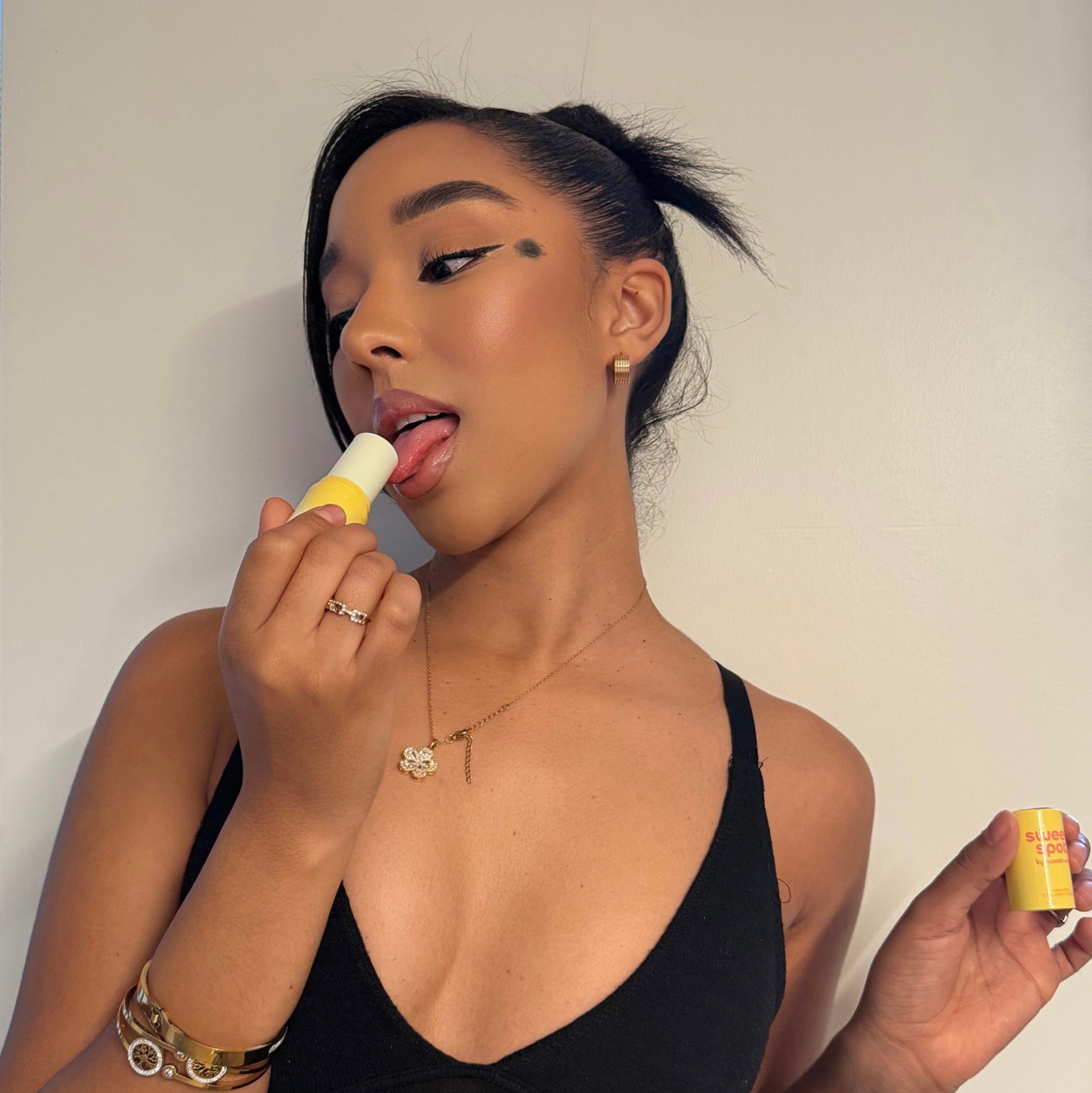 Woman applying Mango Hibiscus Sweet Spot fragrance against a plain background