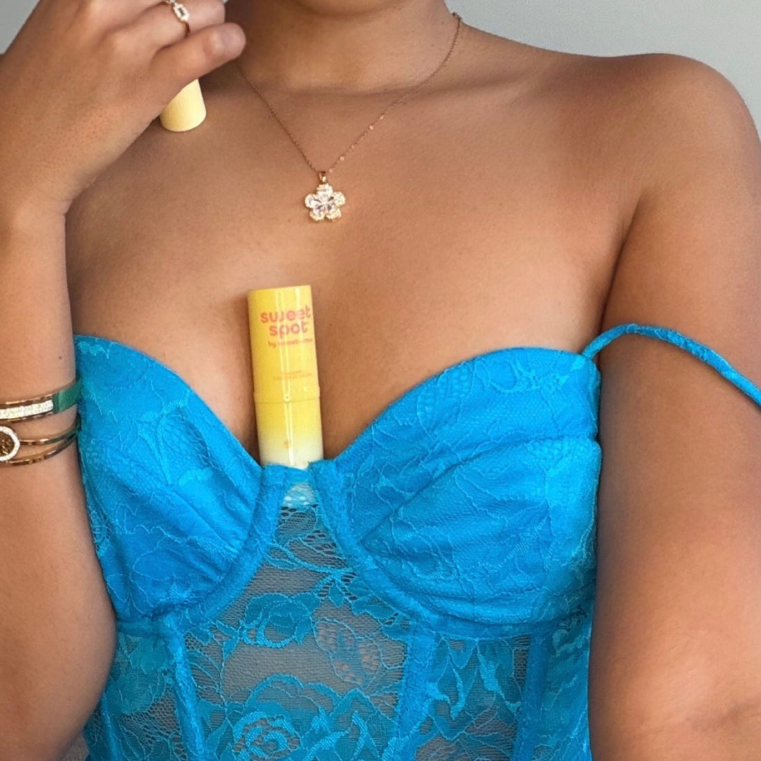 Person wearing a blue lace dress holding a yellow bottle of Sweet Spot flavored fragrance