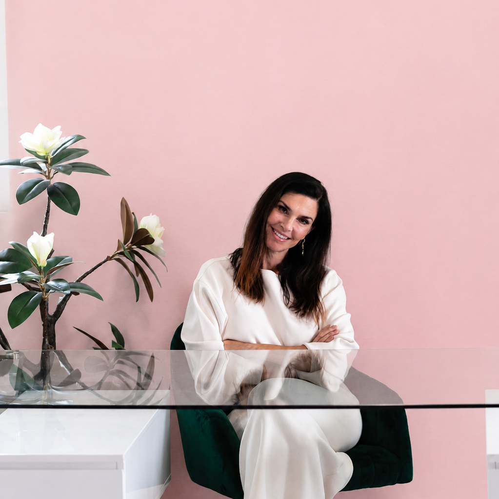 Dr Alisa Brady the Founder of Sweetums sitting in a chair with a pink background