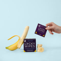 a woman's hand pulling a banana flavored lucky wipe out of a box of the wipes