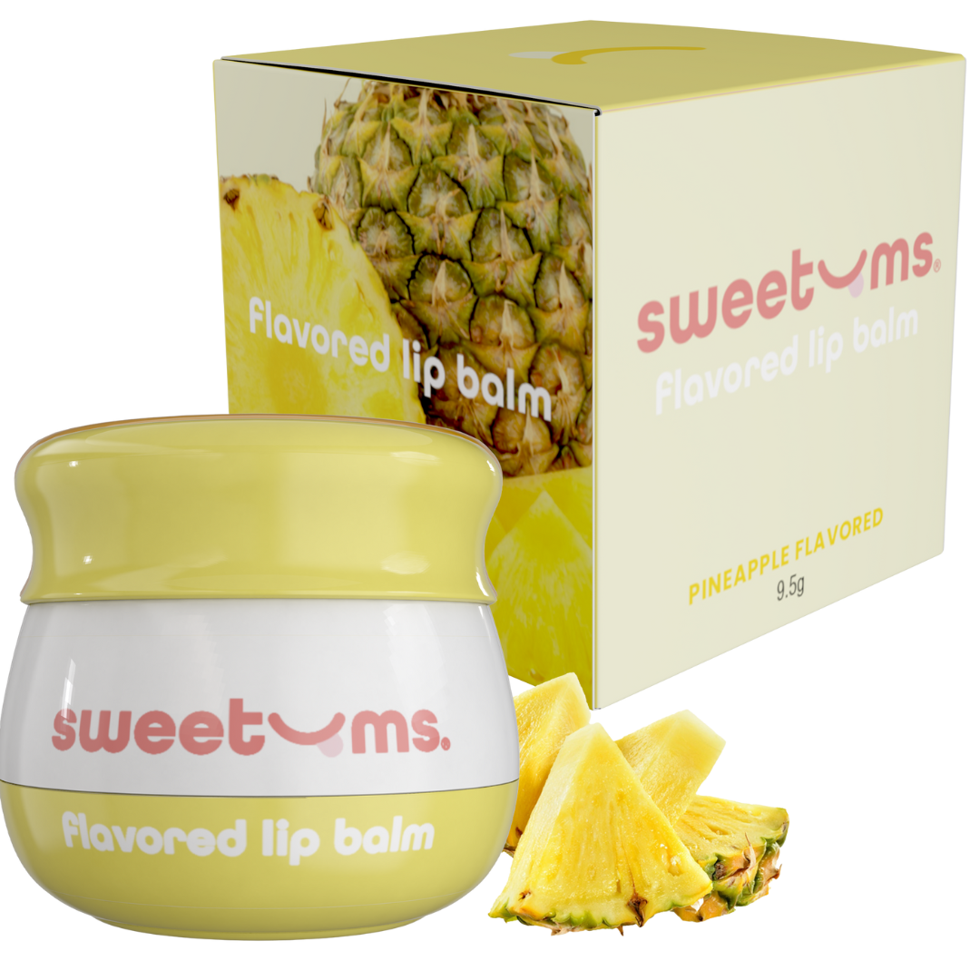 Sweetums pineapple-flavored lip balm with packaging and pineapple slices on a white background