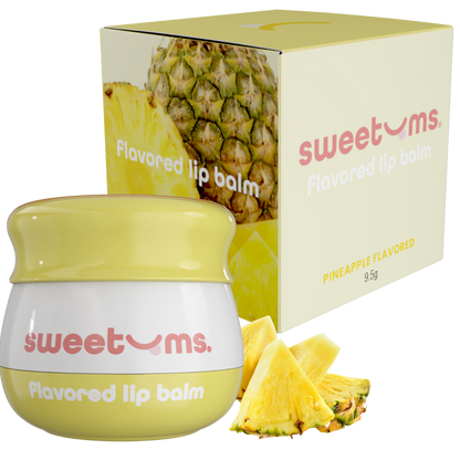 Sweetums pineapple-flavored lip balm with packaging and pineapple slices on a white background